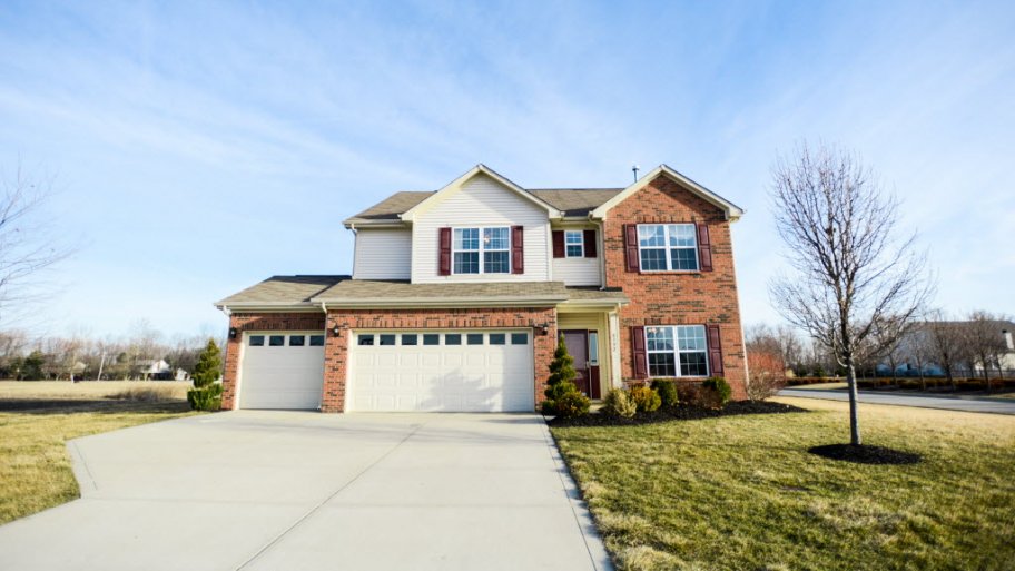 Two-story brick and wood home with driveway and landscaping
